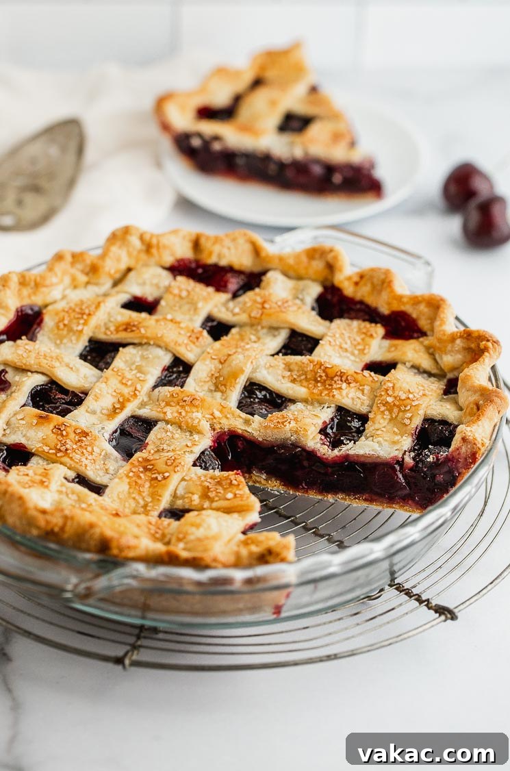 A freshly baked homemade cherry pie with a lattice crust, a slice removed to reveal the vibrant red cherry filling, cooling on a wire rack.