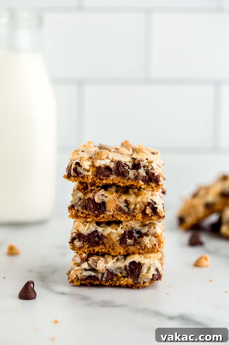 Ultimate Layered Indulgence 2 A stack of golden brown magic cookie bars sitting on a clean marble surface, showcasing their delicious layers.