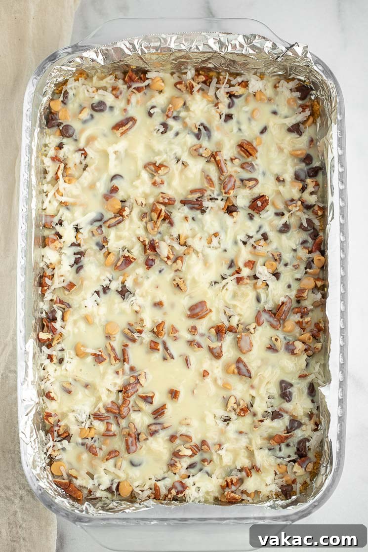 Ultimate Layered Indulgence 4 A 9x13 inch pan filled with all the delicious layers for magic cookie bars, ready for baking.