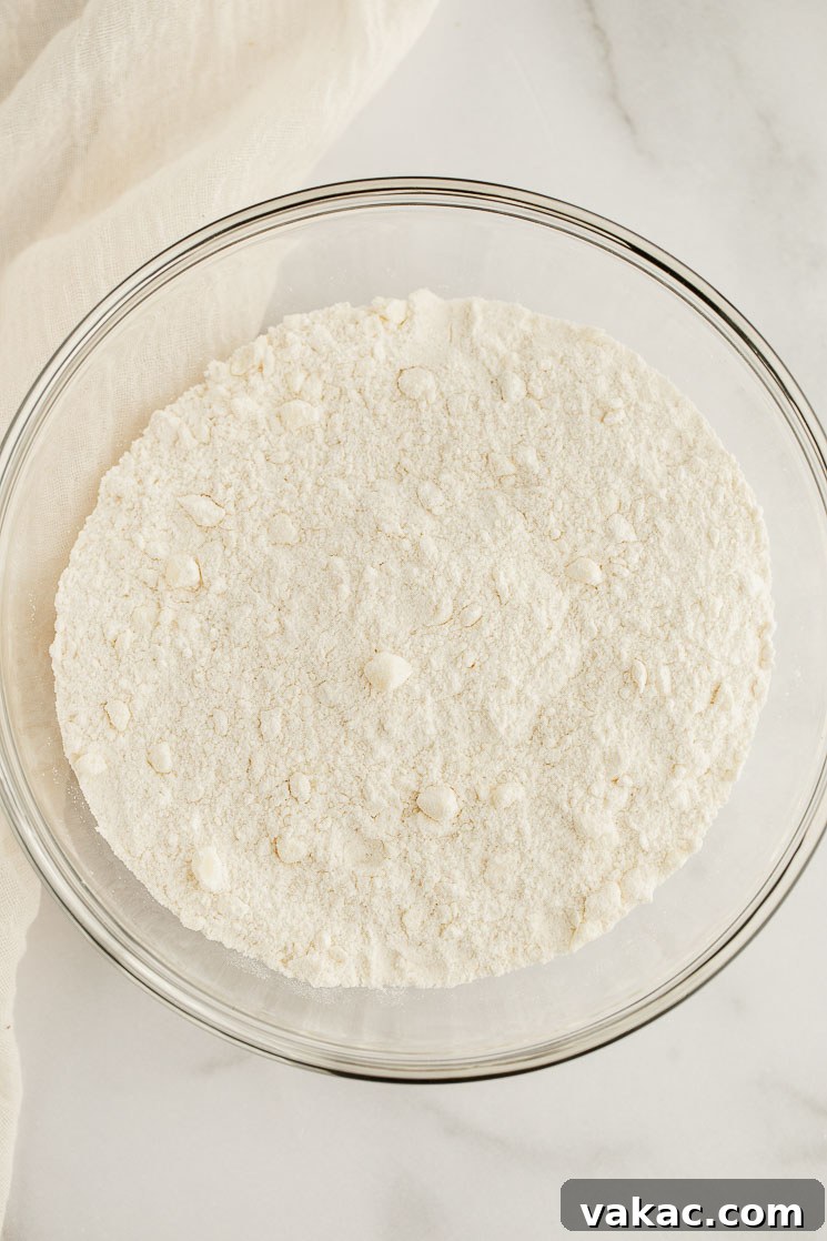 Perfectly Fluffy Scones 4 A close-up view of the dry ingredients, including flour, granulated sugar, baking powder, and salt, perfectly mixed together in a clear glass bowl, showcasing their fine texture.