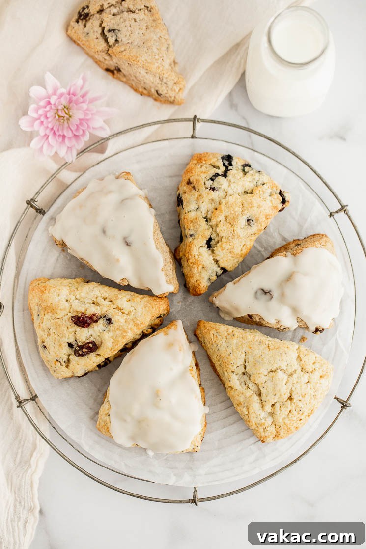 Perfectly Fluffy Scones 7 An inviting assortment of glazed and unglazed scones arranged artfully in a circle on a wire cooling rack, with a glass of milk and an additional scone subtly placed in the background, creating a charming scene.