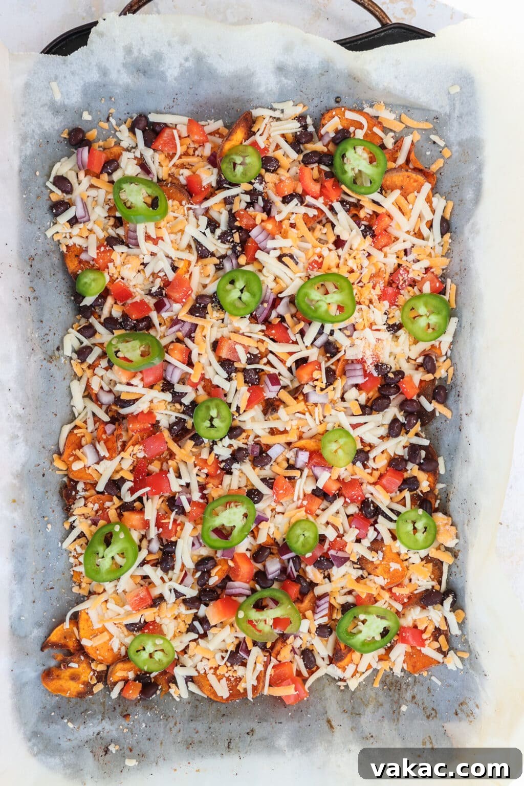 Healthy Sweet Potato Nachos with Black Beans and Bell Peppers 5 Healthy Black Bean & Bell Pepper Sweet Potato Nachos on a baking sheet with parchment paper