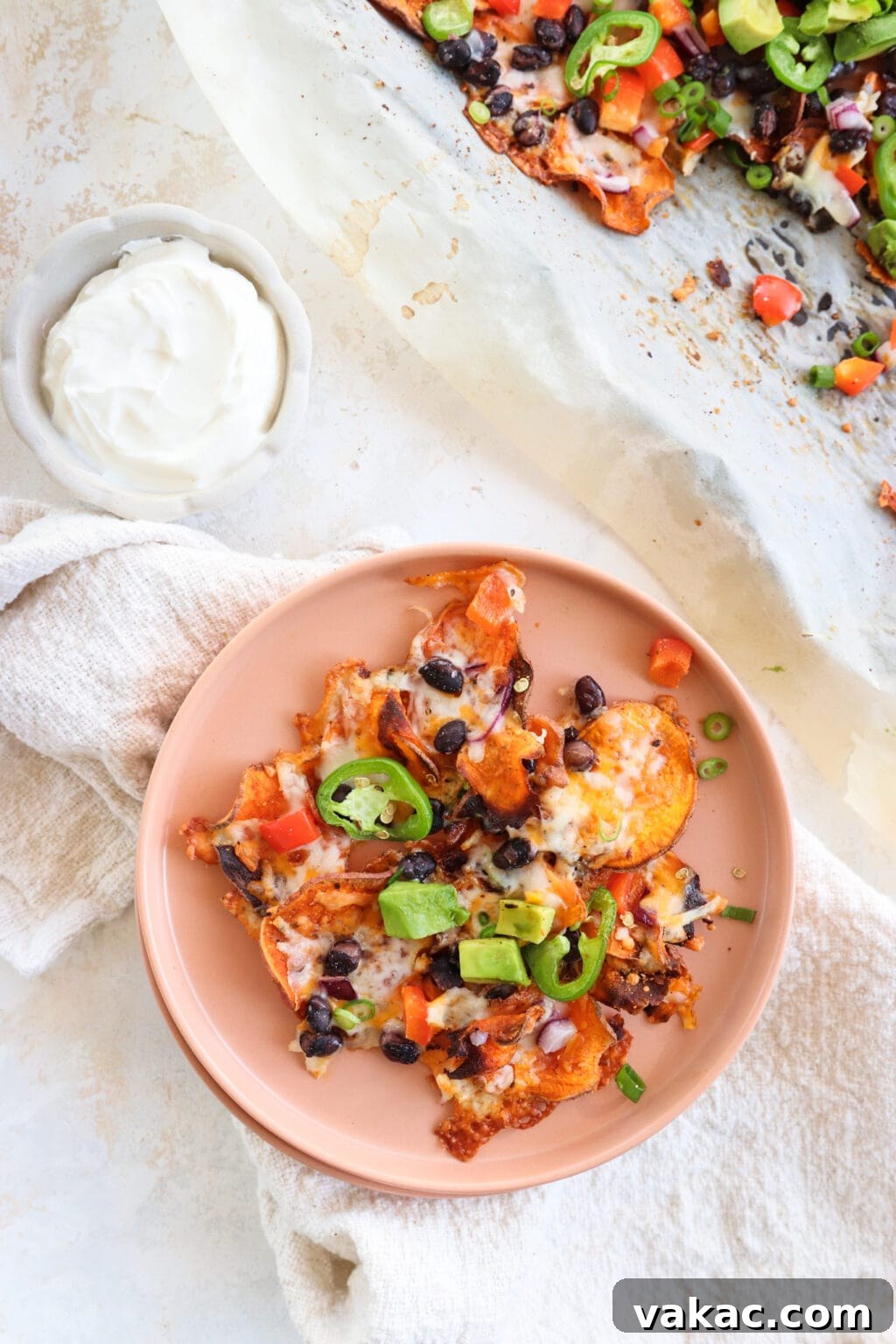 Healthy Sweet Potato Nachos with Black Beans and Bell Peppers 6 Healthy Black Bean & Bell Pepper Sweet Potato Nachos on a pink plate with sour cream on the side