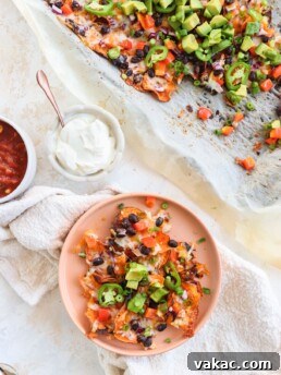 Healthy Black Bean & Bell Pepper Sweet Potato Nachos on a pink plate with salsa and sour cream