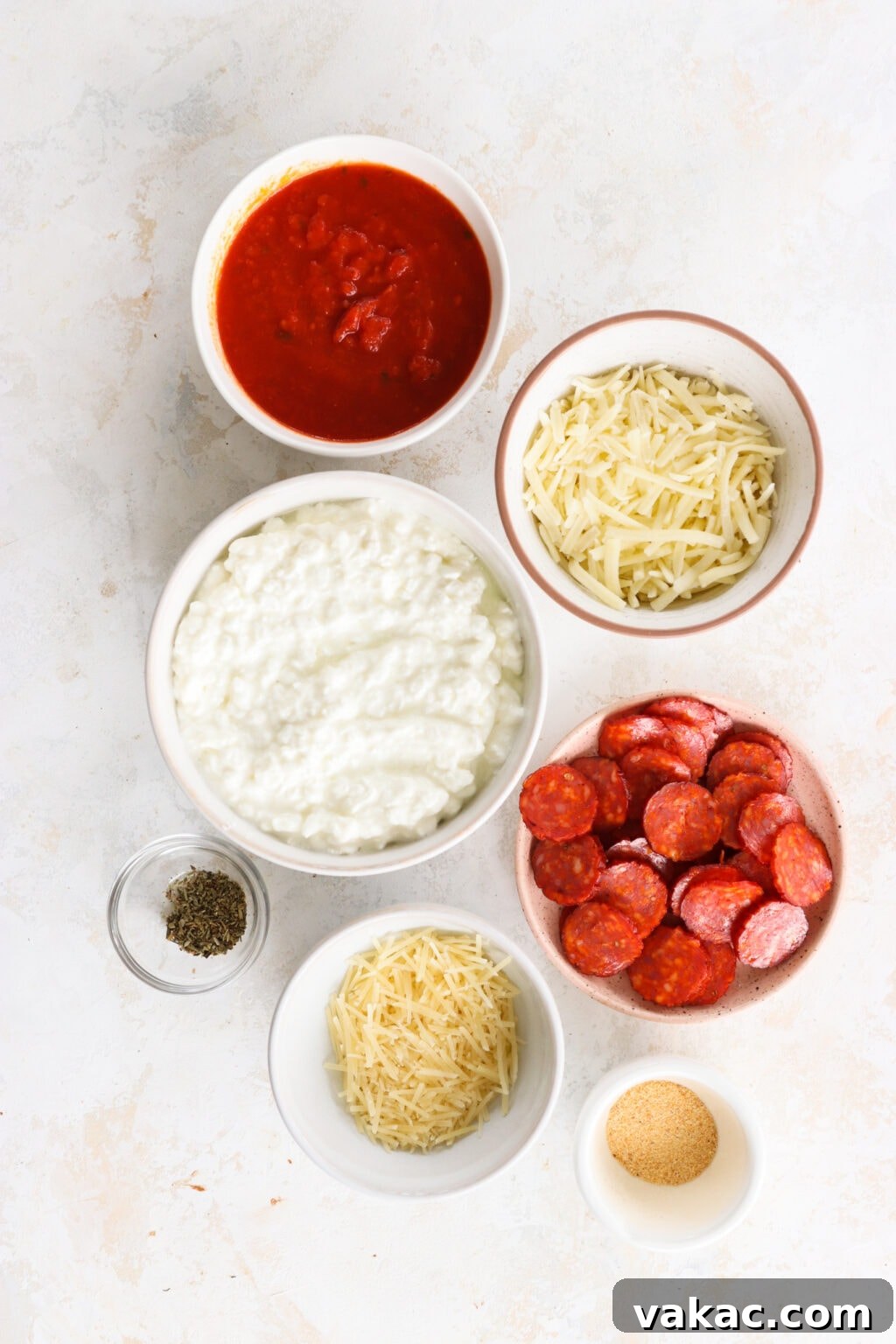 Speedy Cottage Cheese Pizza Dip Bake 3 Ingredients for Quick Baked Cottage Cheese Pizza Bowl Dip in white bowls, including cottage cheese, parmesan cheese, garlic powder, Italian seasoning, marinara sauce, mozzarella cheese, turkey pepperoni or pepperoni