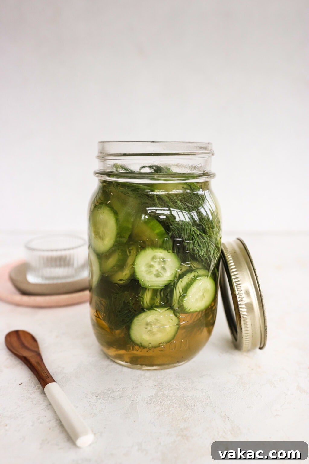 Zesty Apple Cider Vinegar Dill Pickles 2 Apple Cider Vinegar Cucumber Pickles with Dill in a pickle jar with a wooden spoon and glass bowl beside the jar