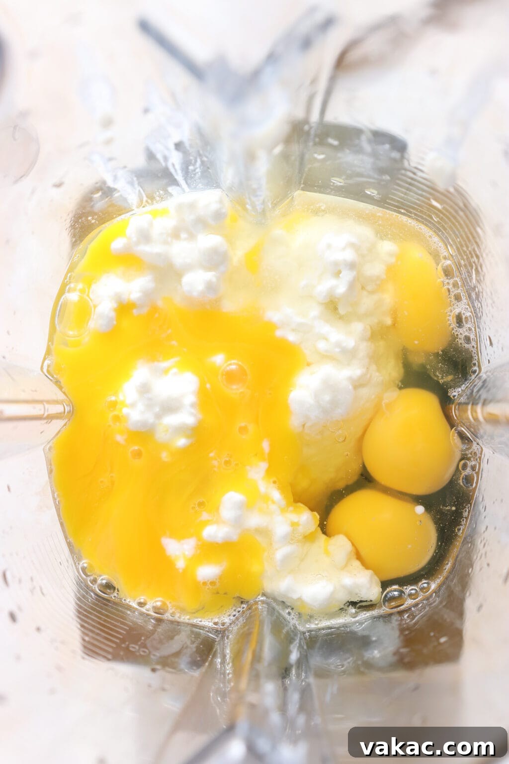 Savory Spinach, Cottage Cheese, and Sun-Dried Tomato Egg Bites 4 Eggs and cottage cheese being added into a blender, ready to be mixed for the Egg Bites recipe