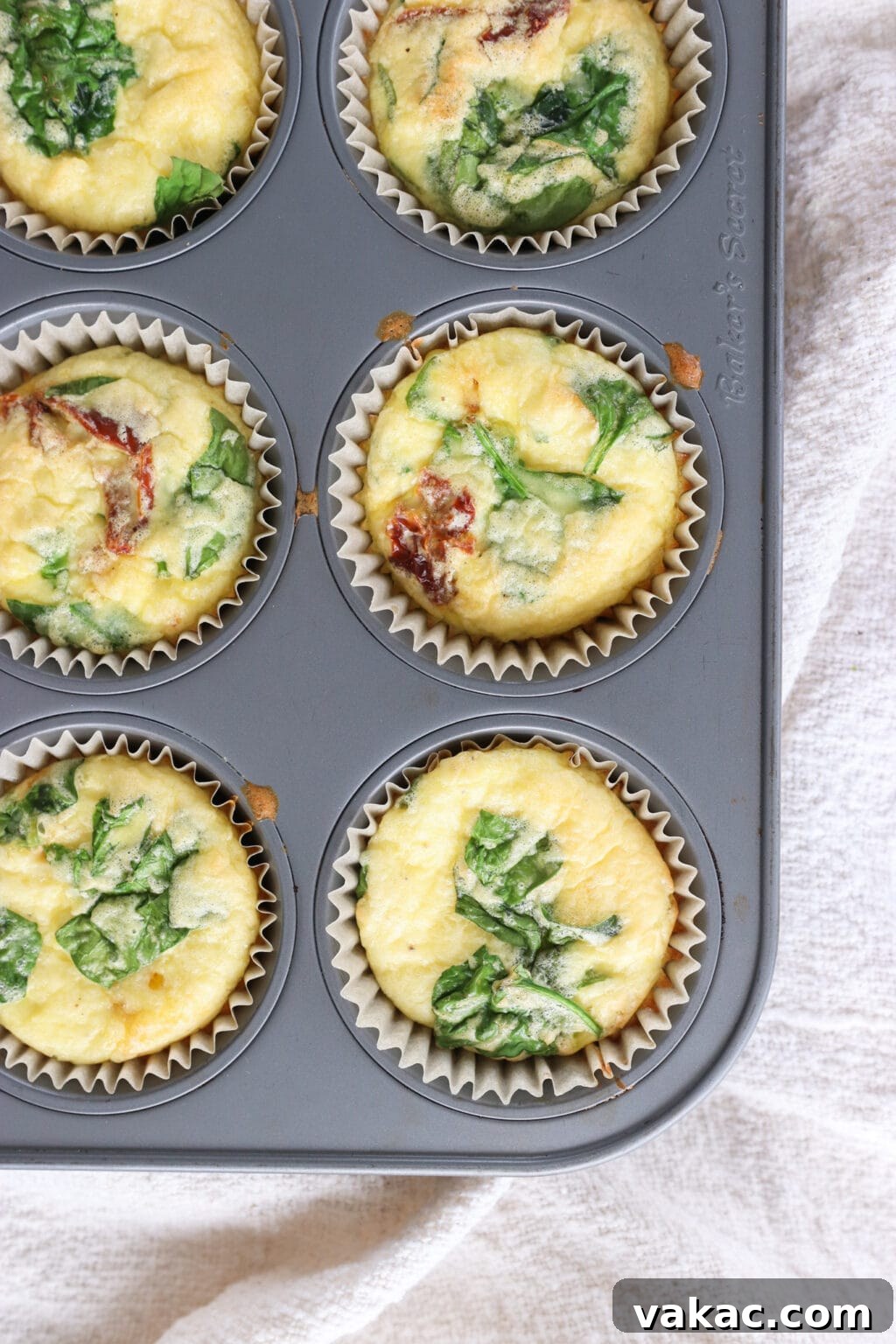 Savory Spinach, Cottage Cheese, and Sun-Dried Tomato Egg Bites 7 Baked Egg Bites with Cottage Cheese, Spinach & Sun-dried Tomatoes cooling in a muffin tin, looking golden and puffy