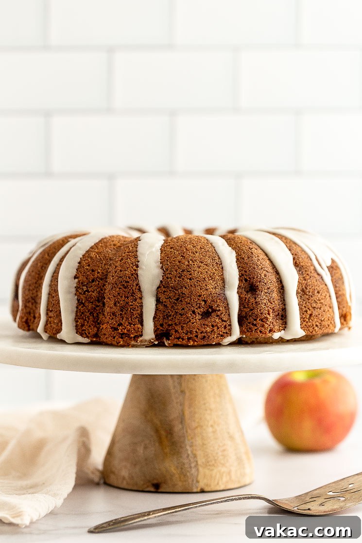 An inviting apple cake beautifully presented on a marble cake stand, ready to be served.