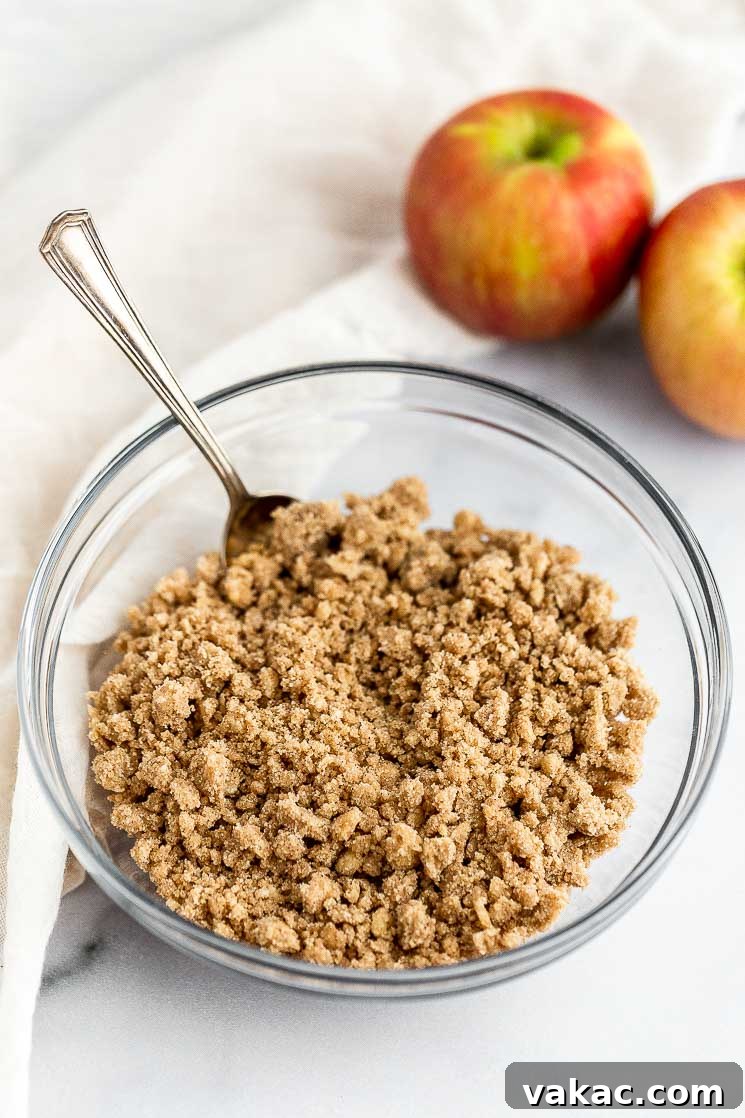 Cinnamon Apple Streusel French Toast Bake 5 A bowl filled with streusel topping, with chopped apples and a baking dish blurred in the background.
