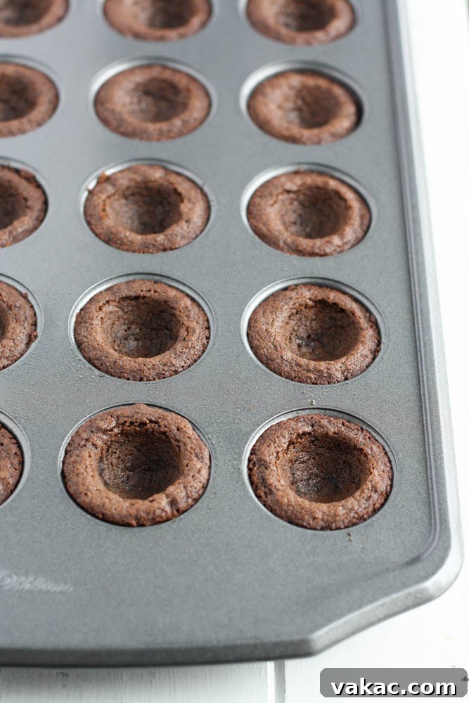 Refreshing Mint Chocolate Cookie Cups 4 A close-up shot of warm chocolate cookie cups being gently pressed in the center with a measuring spoon to create the perfect well for frosting.
