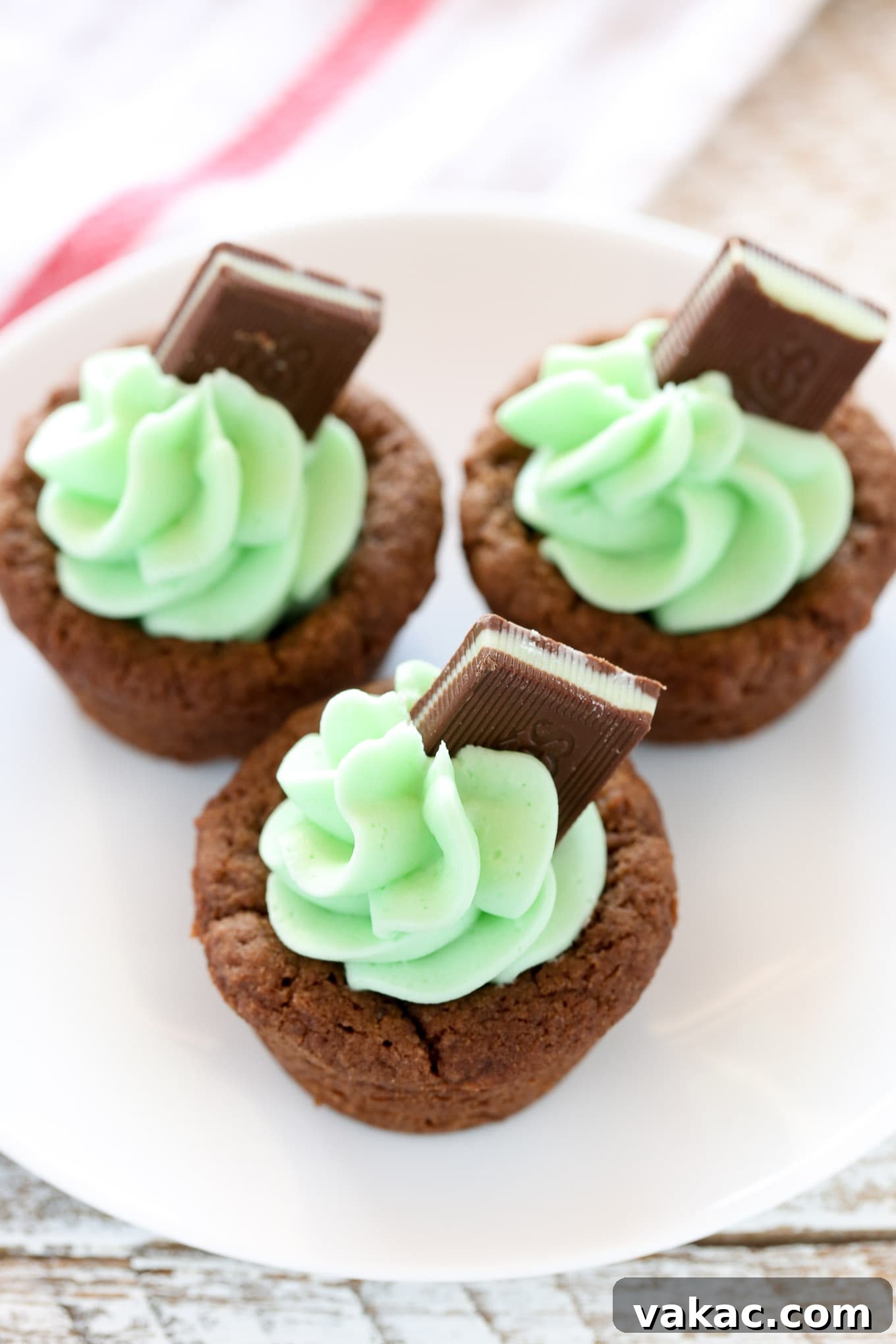 Refreshing Mint Chocolate Cookie Cups 5 Chocolate cookie cups with vibrant green mint frosting piped elegantly on top, adorned with pieces of Andes mints.
