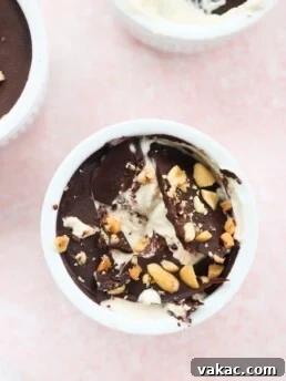 Peanut Butter & Greek Yogurt Cups with Magic Chocolate Shell in white bowls on a pink marble countertop white a scoop taken out of the middle bowl