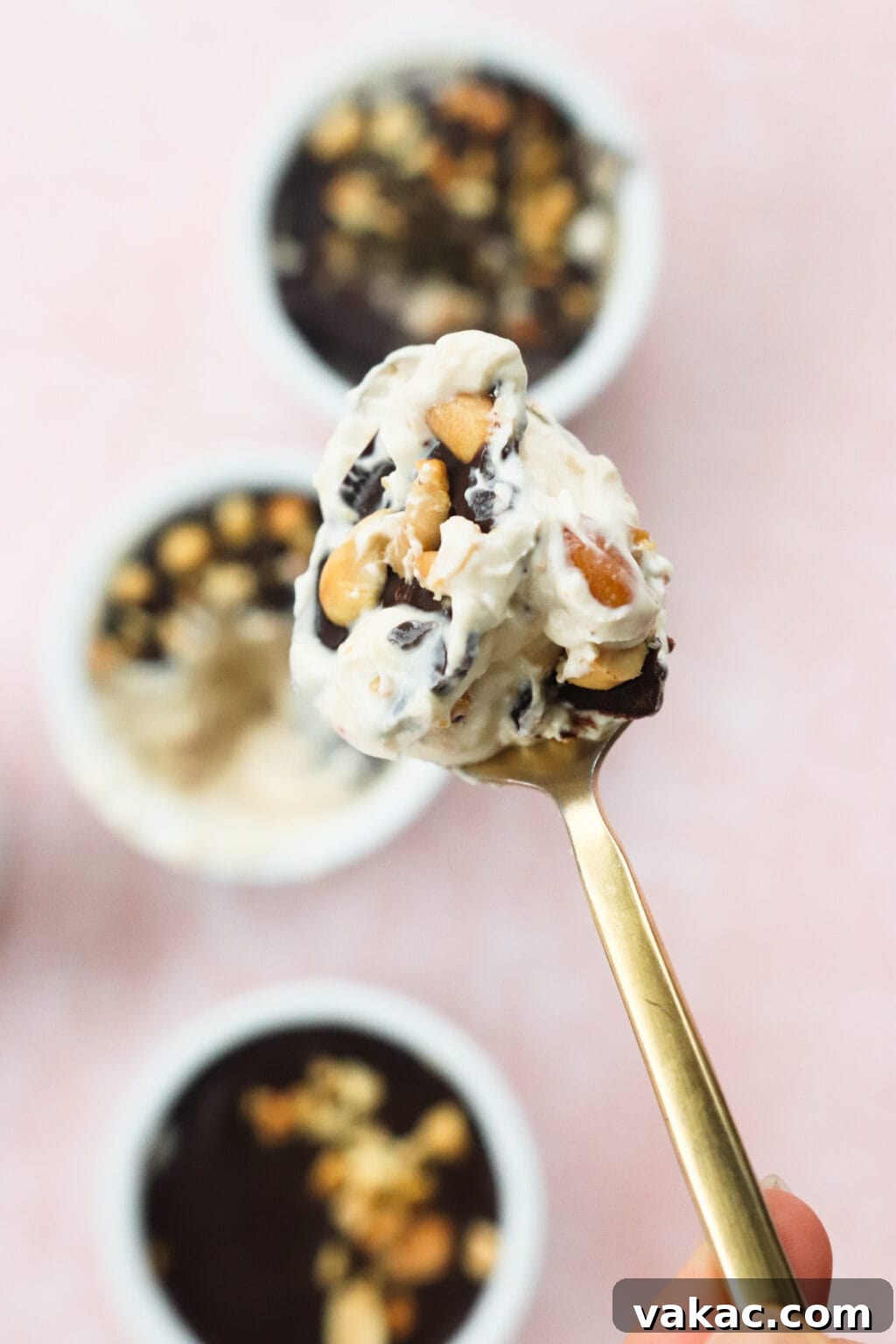 Creamy Peanut Butter and Greek Yogurt Cups with Chocolate Crunch 3 A spoonful of Peanut Butter & Greek Yogurt Cups with Magic Chocolate Shell on a gold spoon with three bowls in the background