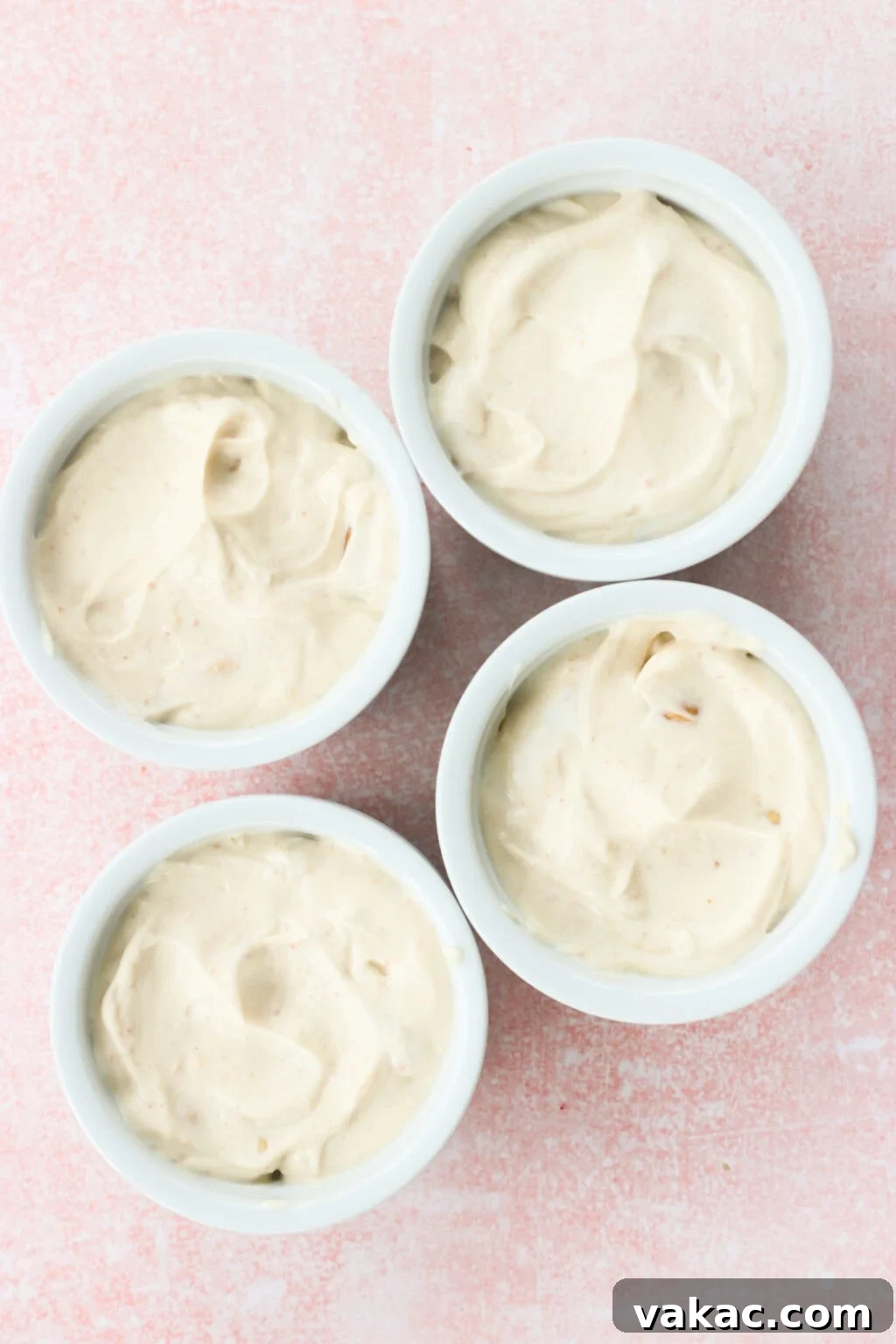 Creamy Peanut Butter and Greek Yogurt Cups with Chocolate Crunch 6 Four white bowls filled with the filling for Peanut Butter & Greek Yogurt Cups with Magic Chocolate Shell on a pink marble countertop
