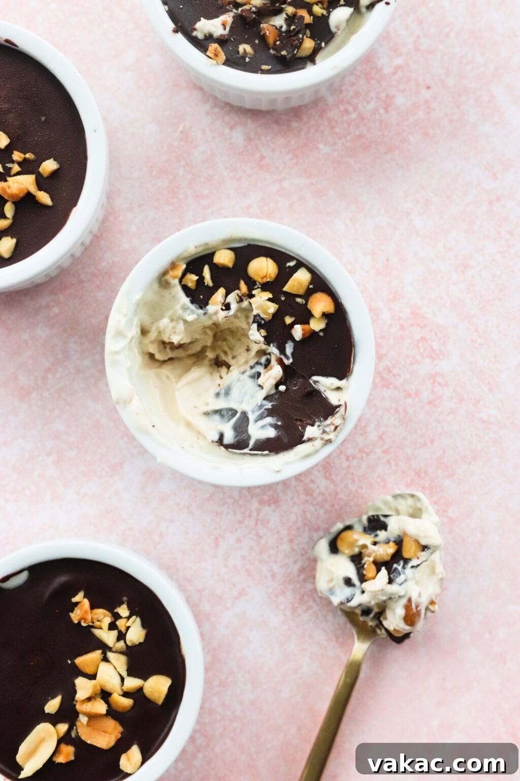 Creamy Peanut Butter and Greek Yogurt Cups with Chocolate Crunch 9 Peanut Butter & Greek Yogurt Cups with Magic Chocolate Shell in white bowls on a pink marble countertop white a scoop taken out of the middle bowl