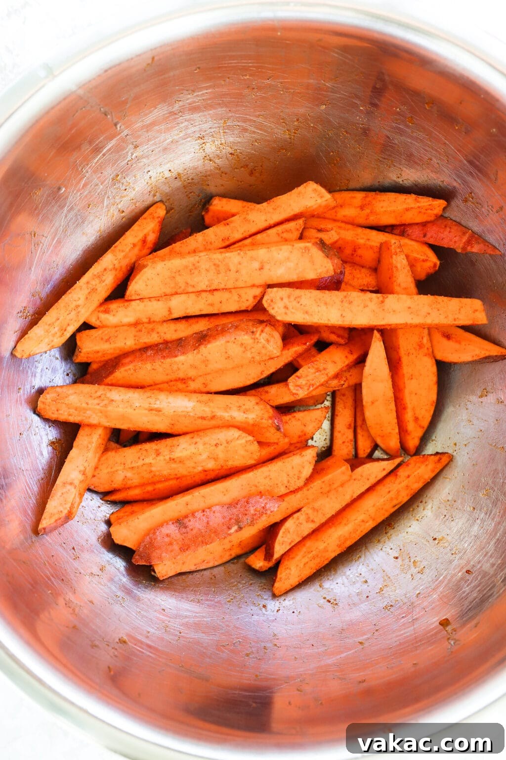 The Ultimate 4-Ingredient Crispy Air Fryer Sweet Potato Wedges 4 Sweet potato wedges seasoned with oil, paprika, and garlic salt, mixed thoroughly in a large bowl.