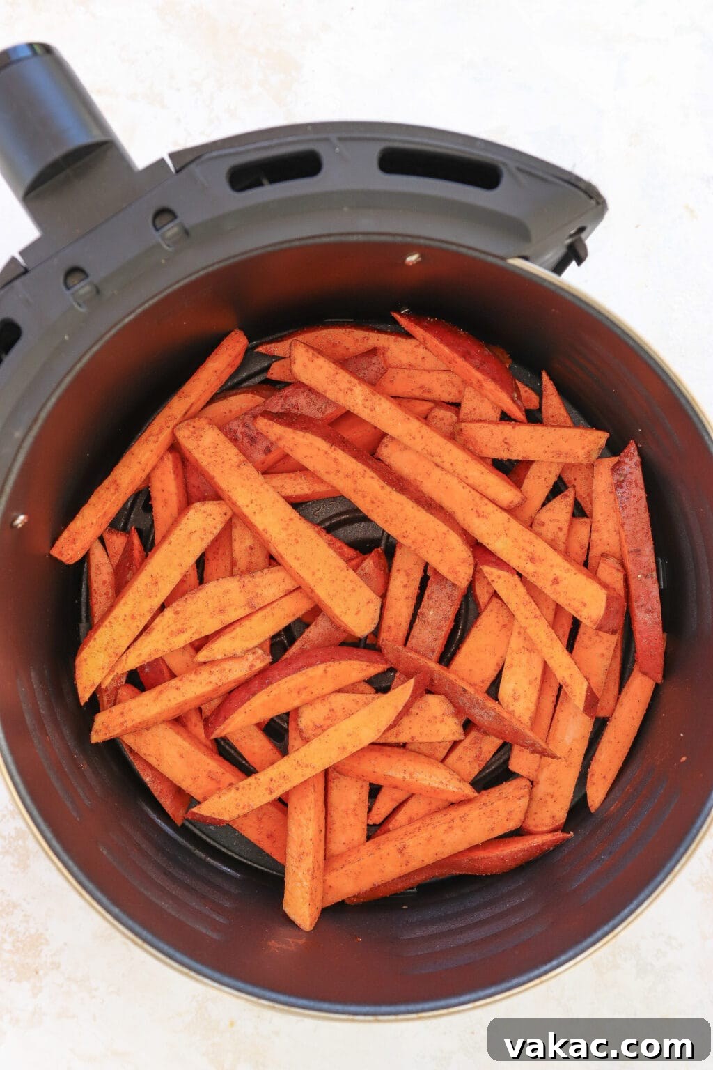 The Ultimate 4-Ingredient Crispy Air Fryer Sweet Potato Wedges 5 Sweet potato wedges arranged in a single layer inside an air fryer basket, ready for cooking.