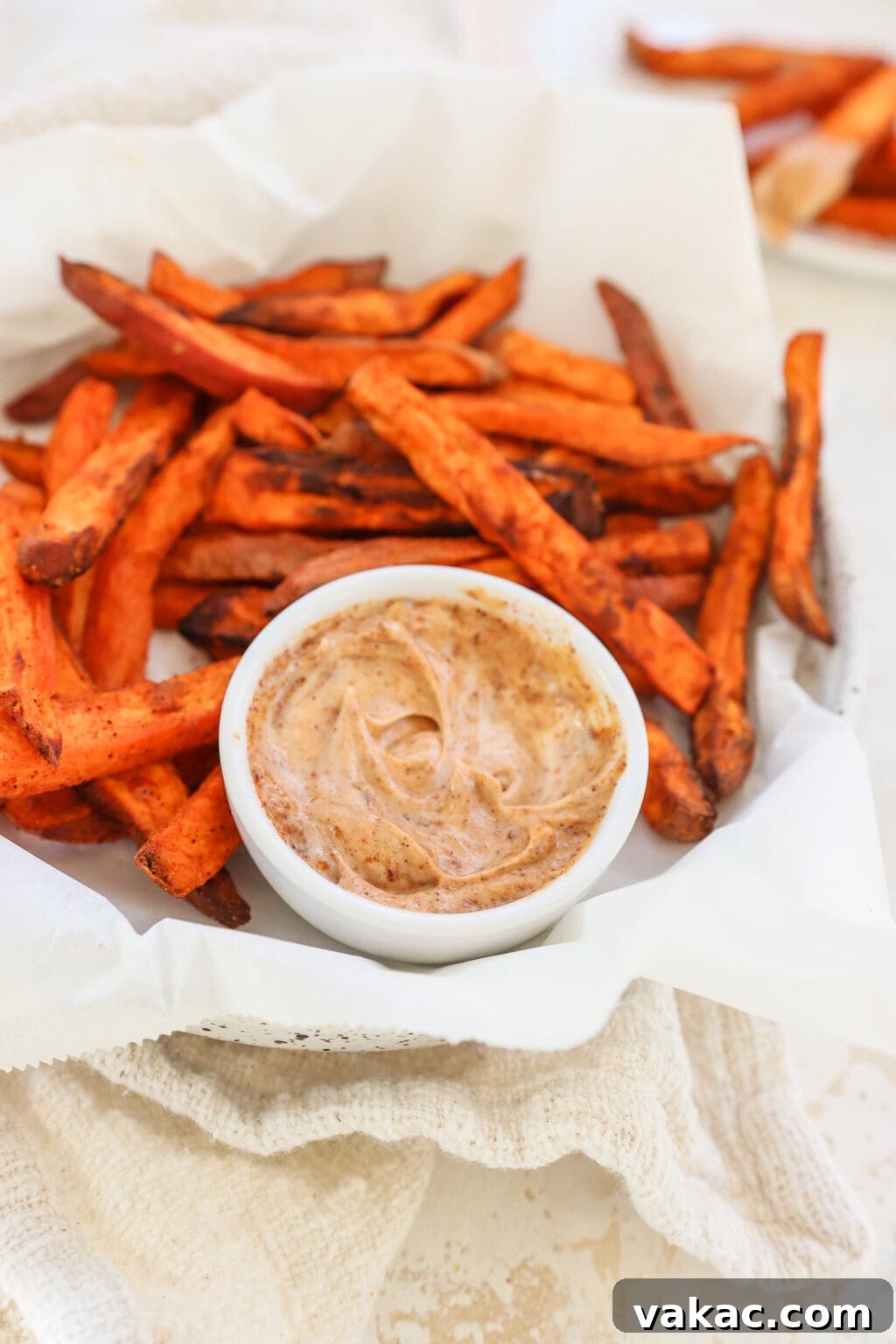 The Ultimate 4-Ingredient Crispy Air Fryer Sweet Potato Wedges 7 A generous serving of crispy air fryer sweet potato wedges in a white bowl, with a small pile on a separate plate for easy snacking.