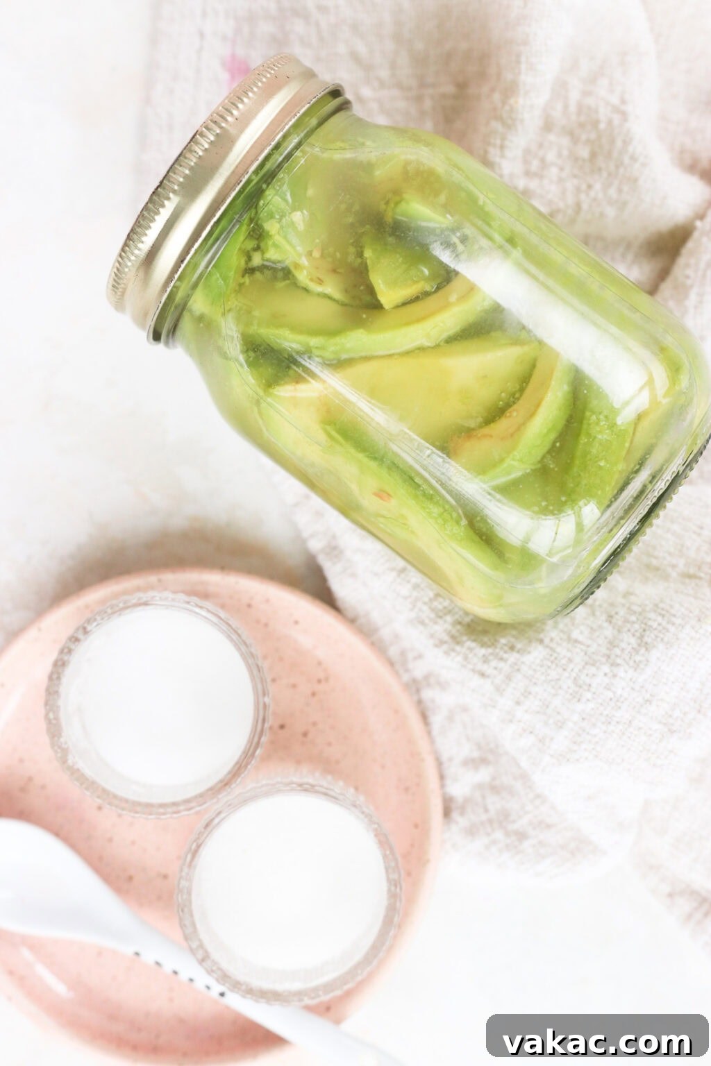 Rapid Tangy Avocados from the Jar 7 The finished quick pickled avocados in a glass jar, presented beautifully on a counter with a pink plate, ready to be stored