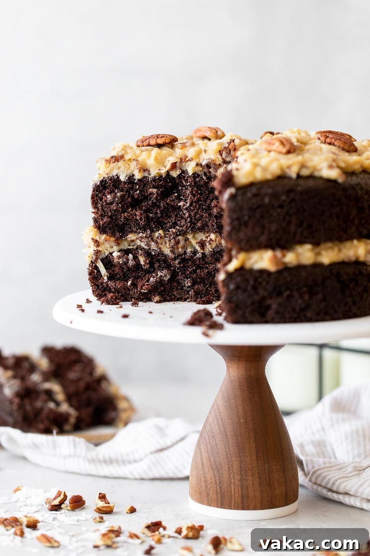 Signature German Chocolate Creation 5 A layered German Chocolate Cake on a marble cake stand with a slice taken out to show the layers more clearly.