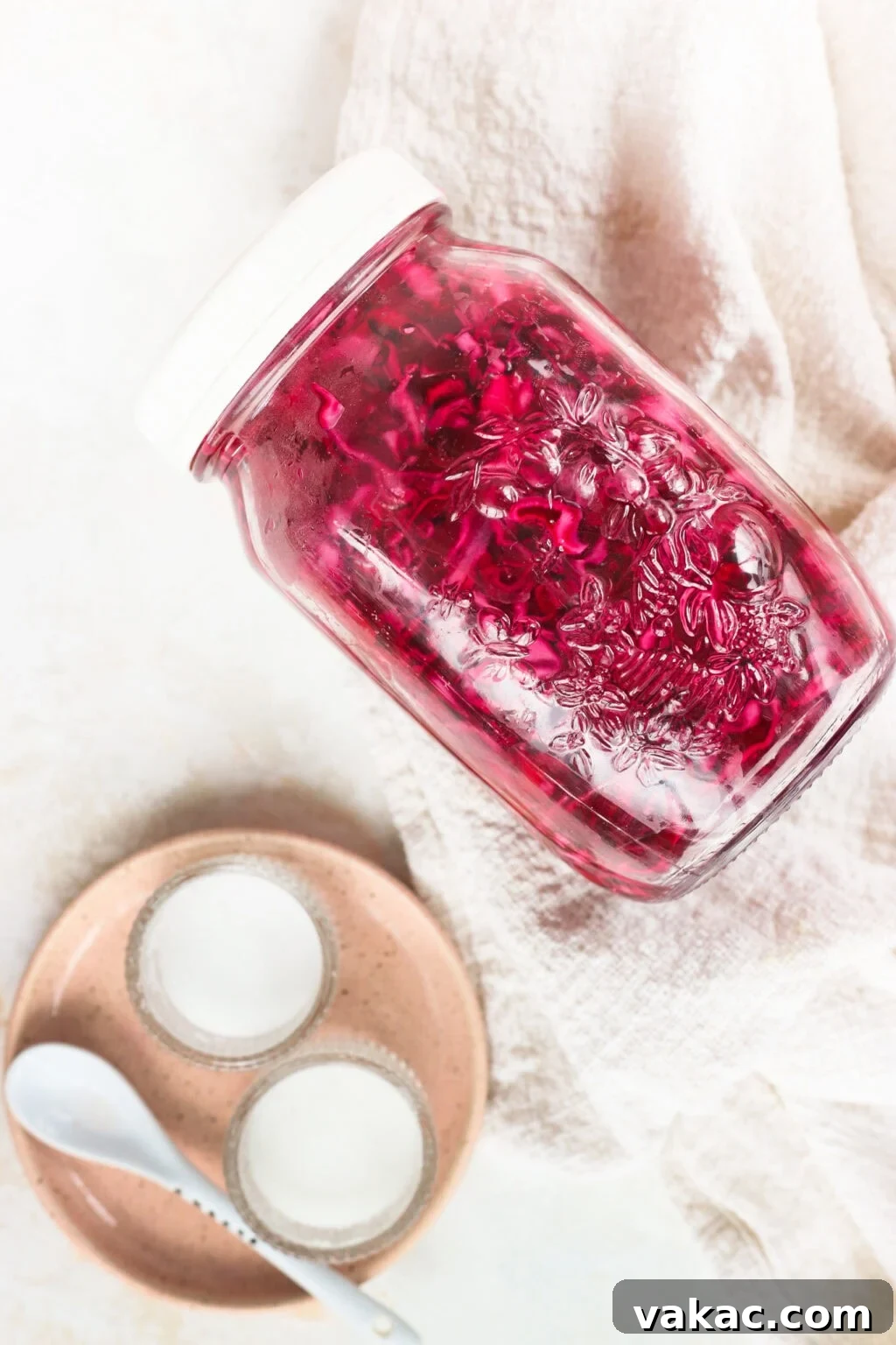 Quick Pickled Red Cabbage Made Easy 2 Quick pickled red cabbage in a glass jar with a pink plate beside it, highlighting its vibrant color and freshness