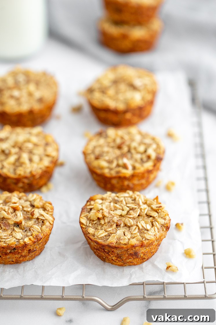 A cooling rack lined with parchment paper, holding multiple golden-brown banana baked oatmeal cups, fresh from the oven and ready to cool.