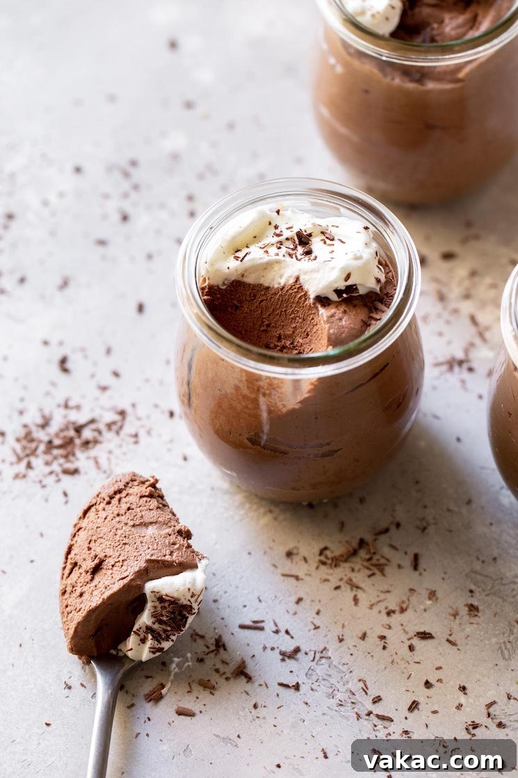 Velvet Chocolate Indulgence 2 Three small jars filled with chocolate mousse topped with whipped cream and chocolate shavings.