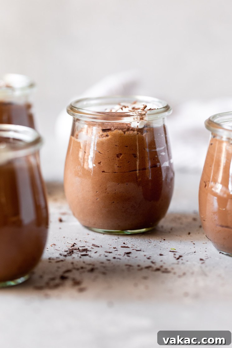 Velvet Chocolate Indulgence 3 Multiple small glass jars filled with chocolate mousse topped with whipped cream and chocolate shavings.