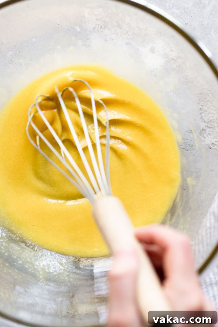 Velvet Chocolate Indulgence 4 A glass bowl with eggs and sugar being mixed together with a whisk.