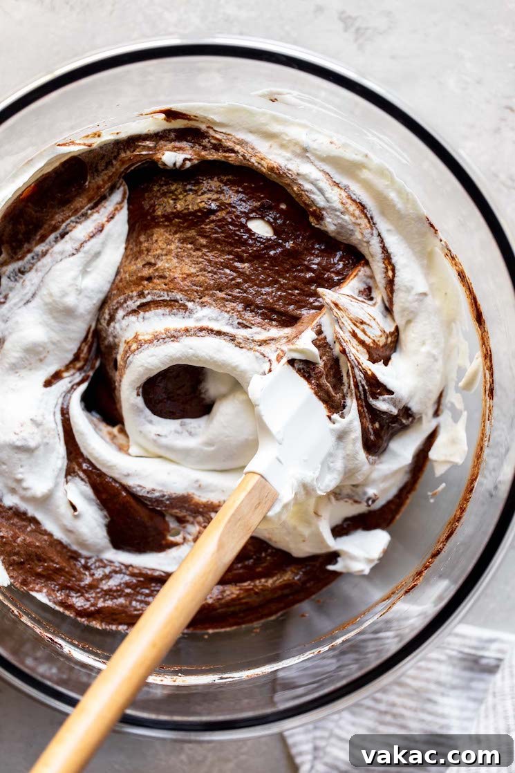 Velvet Chocolate Indulgence 6 A glass mixing bowl with the chocolate mixture and whipped cream being mixed together with a rubber spatula.