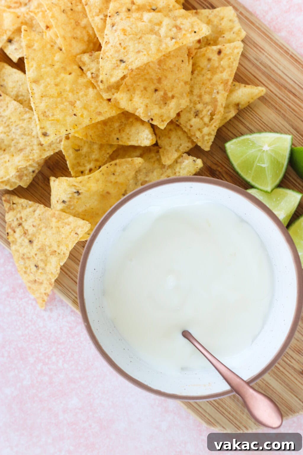 Just 4 Ingredients for Tangy Greek Yogurt Lime Crema 7 A bowl of creamy Greek Yogurt Lime Crema beautifully presented on a wooden butcher block, accompanied by a side of tortilla chips, suggesting a perfect dipping experience.