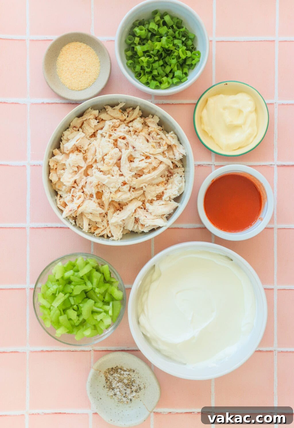 Fast Protein-Packed Buffalo Chicken Salad with Greek Yogurt 3 Ingredients for Quick Buffalo Chicken Salad with Greek Yogurt in small white bowls including cooked shredded chicken, Greek yogurt, mayo, Frank's Red Hot Original Sauce, garlic powder, green onions, blue cheese, pepper