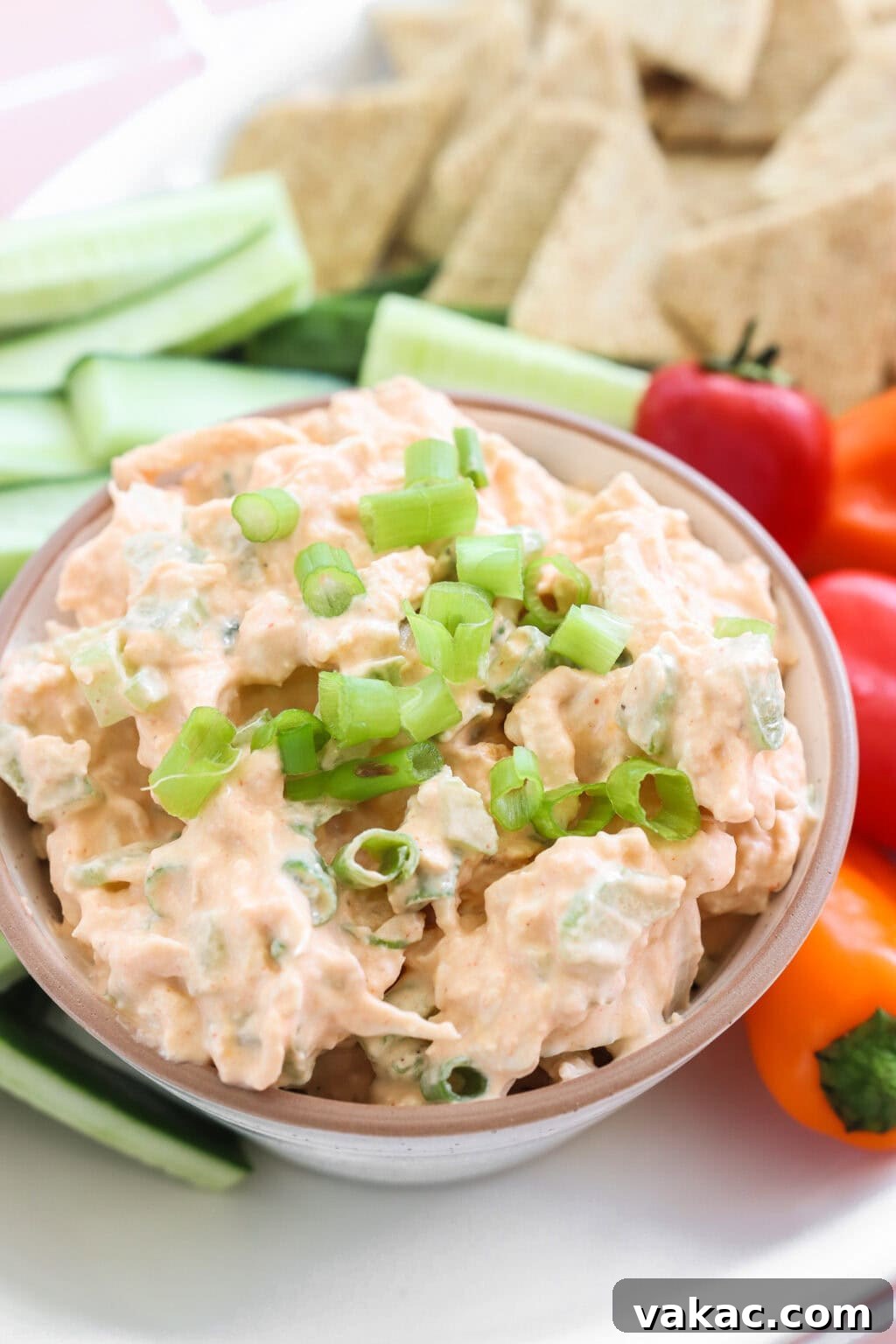 Fast Protein-Packed Buffalo Chicken Salad with Greek Yogurt 7 Quick Buffalo Chicken Salad with Greek Yogurt in a glass bowl on a white serving tray with celery, peppers, and crackers on the side