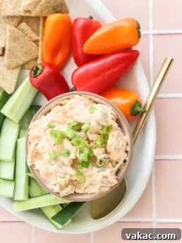 Quick Buffalo Chicken Salad with Greek Yogurt in a glass bowl on a white serving tray with celery, peppers, and crackers on the side