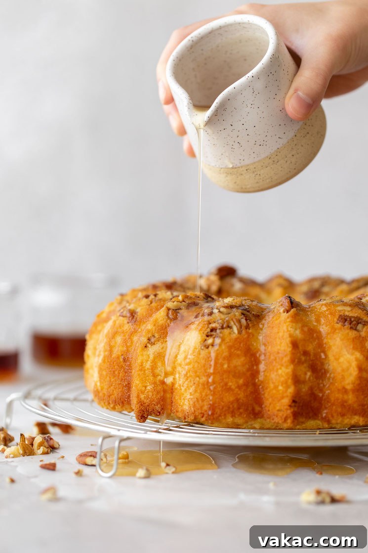 Golden Rum Cake Delight 2 A baked rum cake resting on a round cooling rack and the rum glaze being poured over the top.