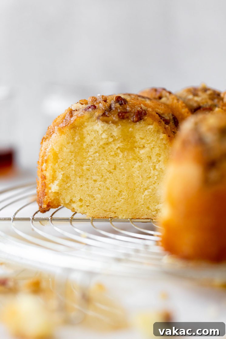 Golden Rum Cake Delight 6 A finished rum cake resting on a round cooling rack with a slice cut out to show the cake texture.