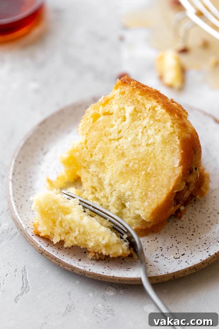 Golden Rum Cake Delight 7 A single slice of cake on a rustic clay plate and a bite taken out with a fork.