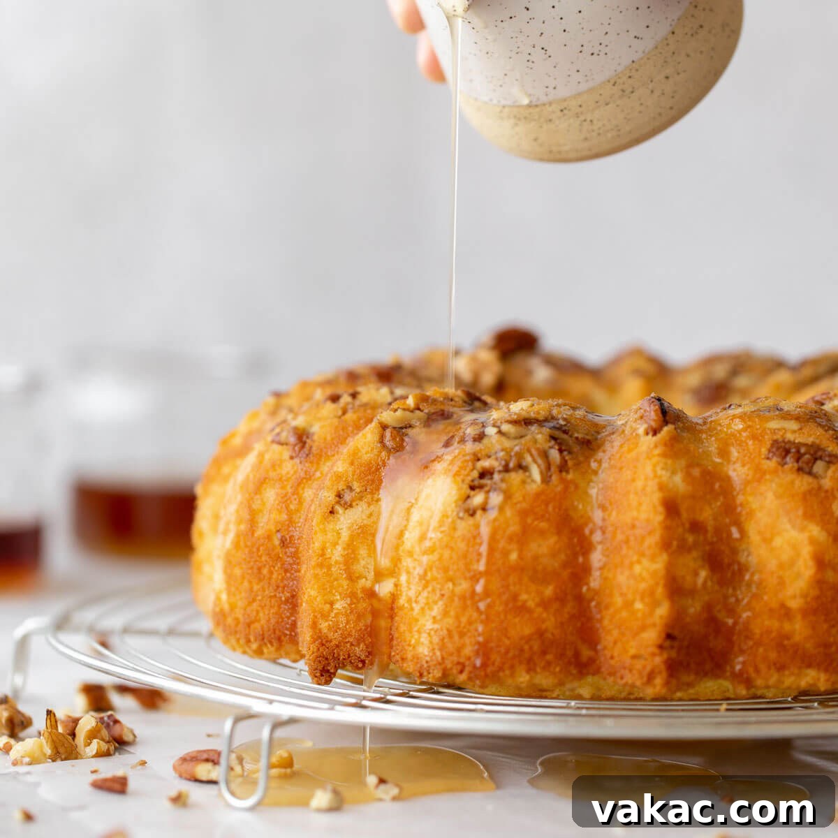 Golden Rum Cake Delight 8 A baked rum cake resting on a round cooling rack and the rum glaze being poured over the top.