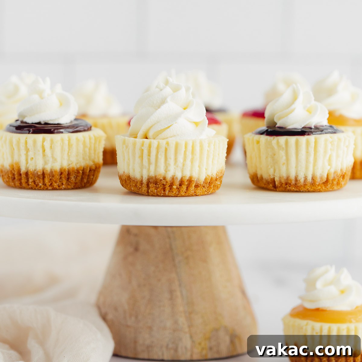 Several mini cheesecakes with different toppings on a marble cake stand.