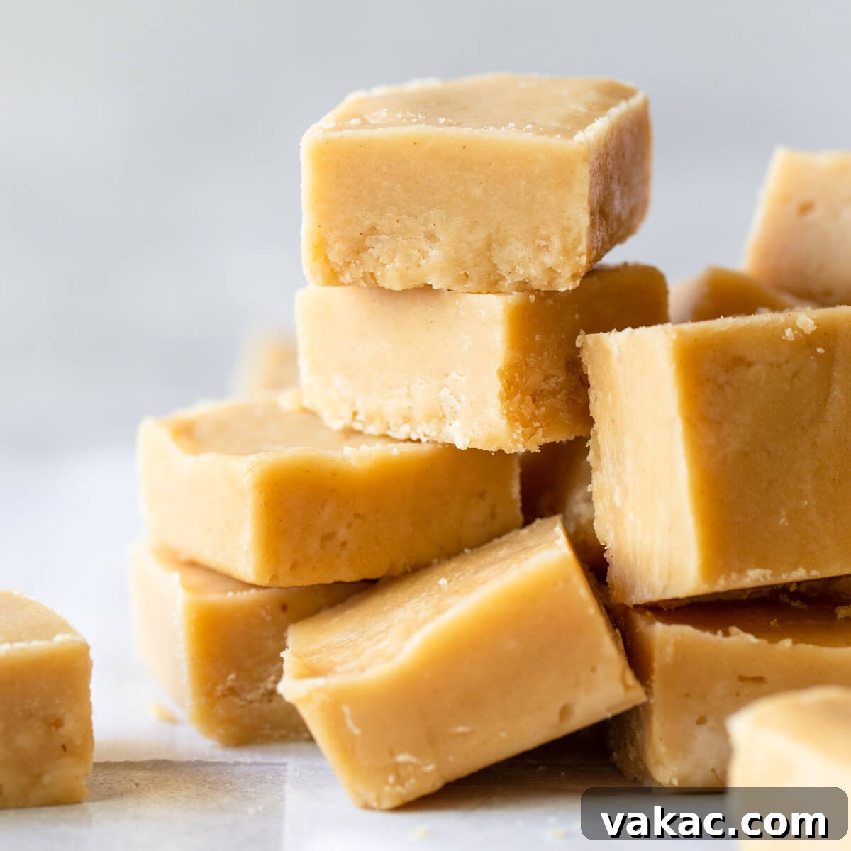 Ultimate Peanut Butter Fudge 7 Pieces of Peanut Butter Fudge stacked on a gray surface and parchment paper.