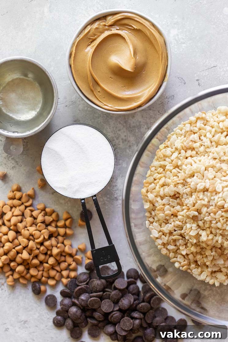 Peanut Butter Butterscotch Crispy Bars 3 All the essential ingredients for making classic Scotcheroos, including corn syrup, granulated sugar, creamy peanut butter, crispy rice cereal, semi-sweet chocolate chips, and butterscotch chips, neatly arranged on a rustic gray surface.