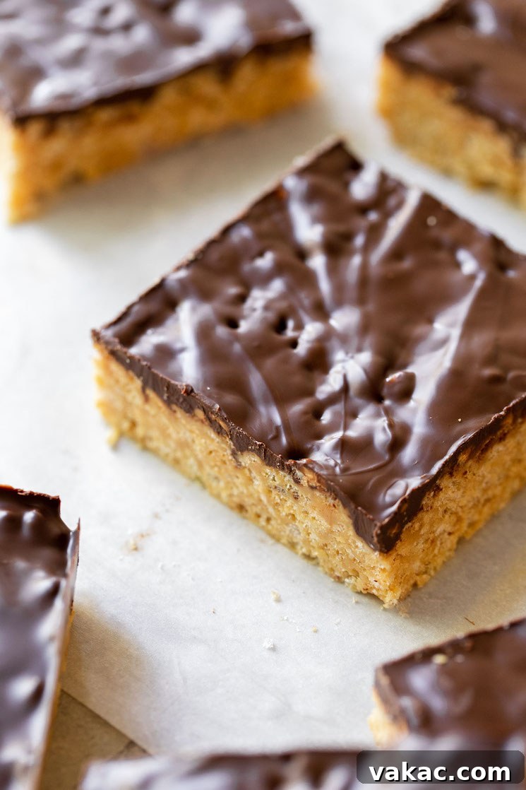 Peanut Butter Butterscotch Crispy Bars 5 A finished Scotcheroo bar, perfectly cut and resting on parchment paper, beautifully revealing the distinct layers of the chewy peanut butter crispy rice base and the smooth, marbled chocolate and butterscotch topping.