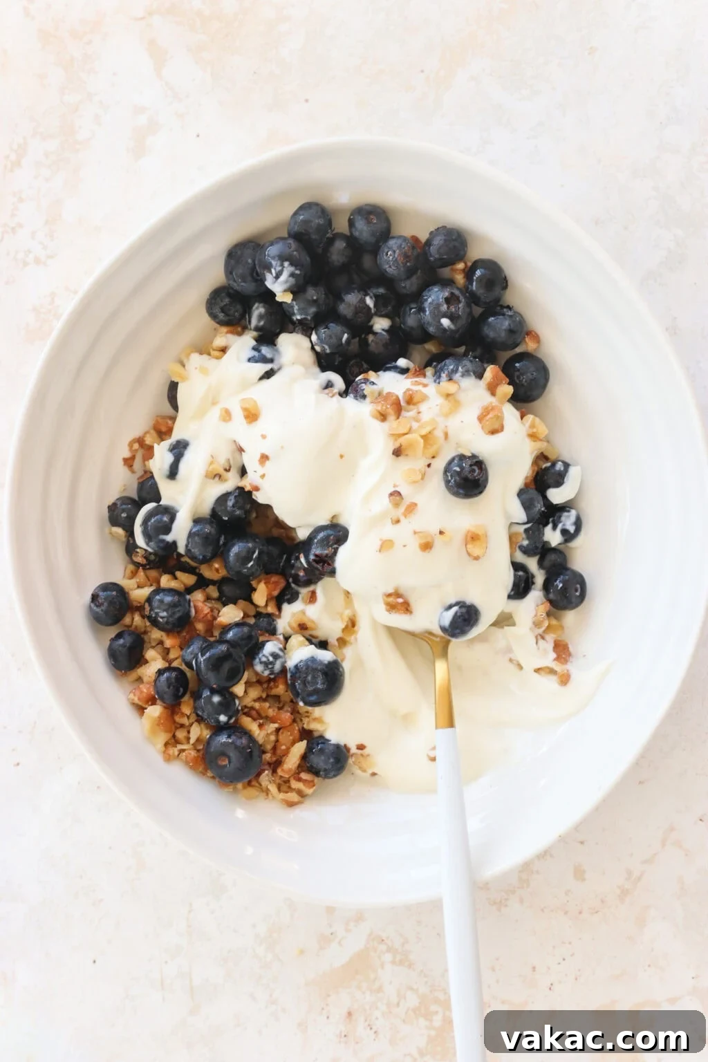 Effortless High-Protein Frozen Greek Yogurt Blueberry Bites 4 Ingredients for Frozen Blueberry Greek Yogurt Clusters added to a white bowl for mixing, including blueberries, walnuts, vanilla Greek yogurt, salt, chocolate chips, coconut oil