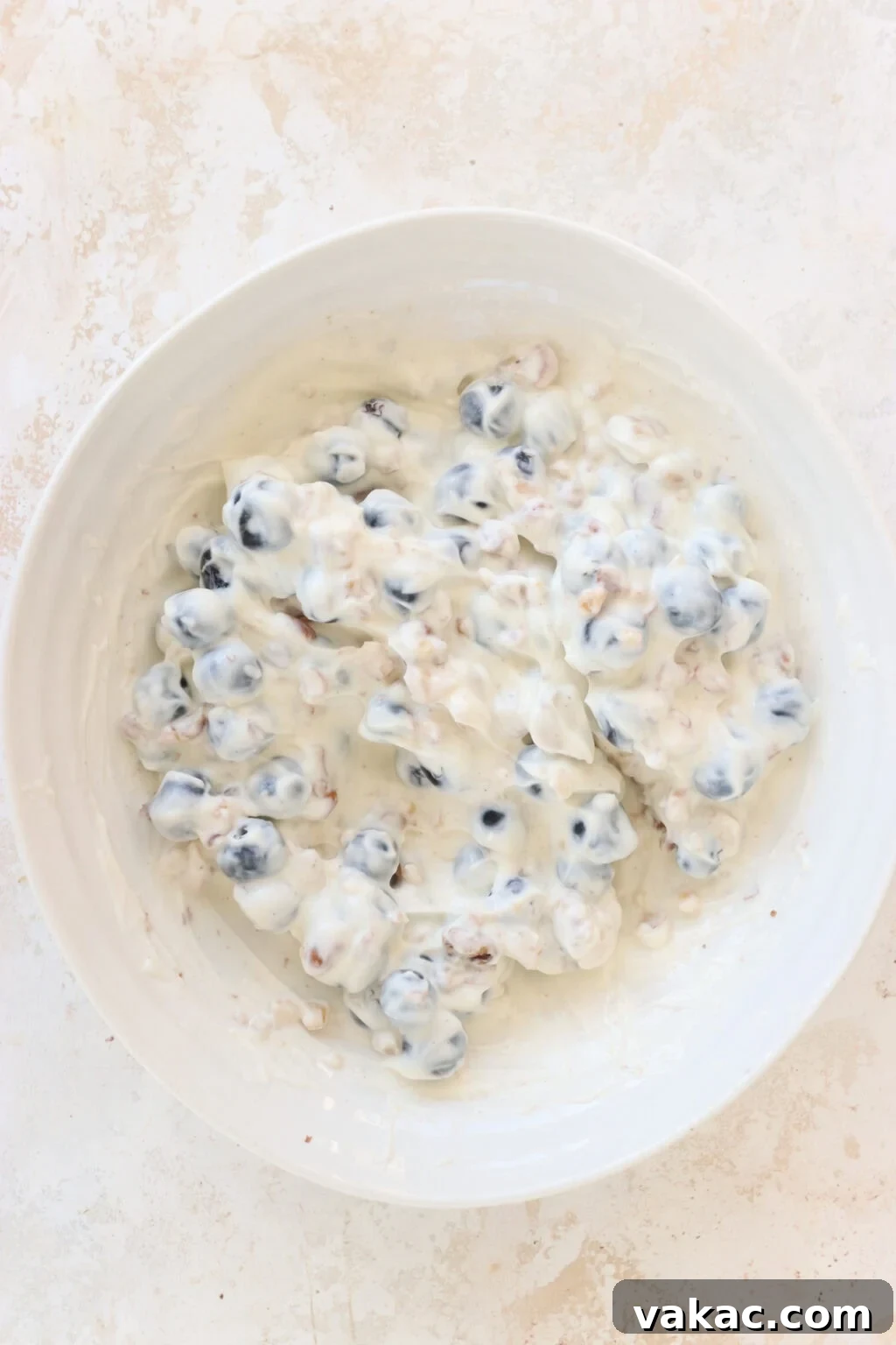 Effortless High-Protein Frozen Greek Yogurt Blueberry Bites 5 Ingredients for Frozen Blueberry Greek Yogurt Clusters mixed in a white bowl, including blueberries, walnuts, vanilla Greek yogurt, salt, chocolate chips, coconut oil