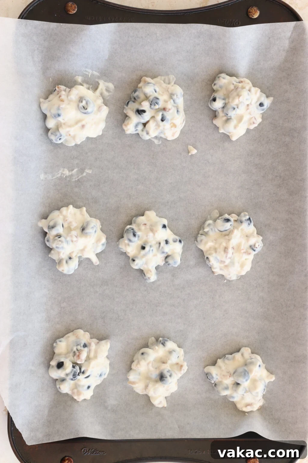 Effortless High-Protein Frozen Greek Yogurt Blueberry Bites 6 Frozen Blueberry Greek Yogurt Clusters on a pan with parchment paper before being dipped in chocolate