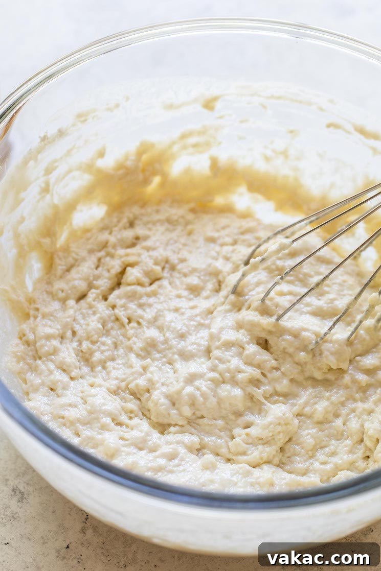 Golden Brew Loaf 4 All the dry and wet ingredients for beer bread mixed together in a clear glass bowl using a metal whisk, showing a thick, cohesive batter.