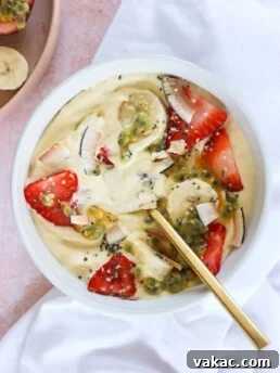 High Protein Tropical Smoothie Bowl with Greek Yogurt in a white bowl with a gold spoon and white tablecloth
