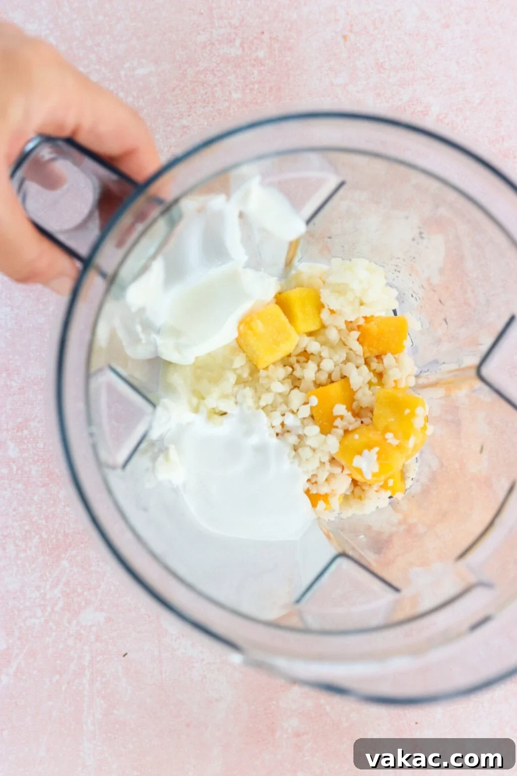 Paradise Protein Greek Yogurt Bowl 4 Ingredients for high protein tropical smoothie bowl with Greek yogurt unblended in a blender, including Greek yogurt, mango, riced cauliflower, lime juice, milk of choice
