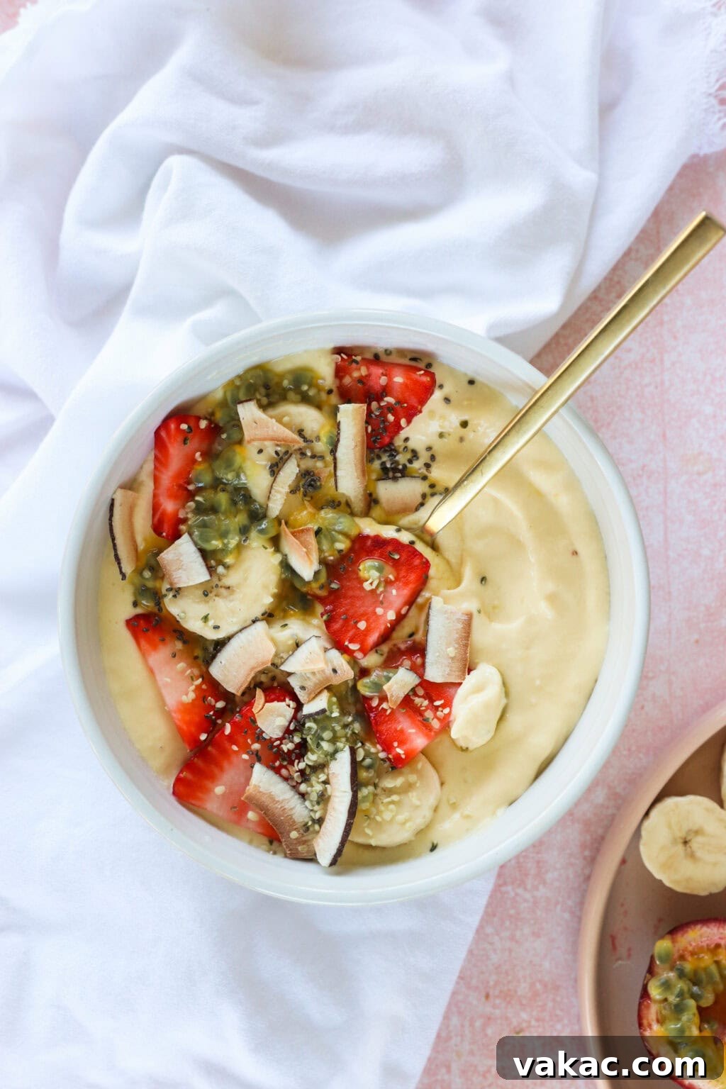 Paradise Protein Greek Yogurt Bowl 9 High Protein Tropical Smoothie Bowl with Greek Yogurt in a white bowl with a gold spoon and white tablecloth